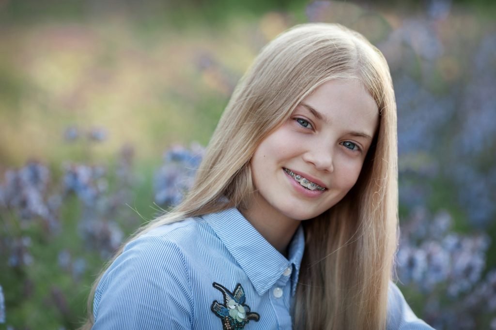 beautiful teen girl with braces on her teeth smiling. portrait of blonde model