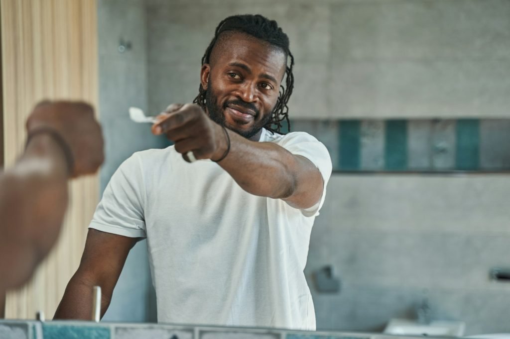 Guy with oral hygiene tool standing in bathroom