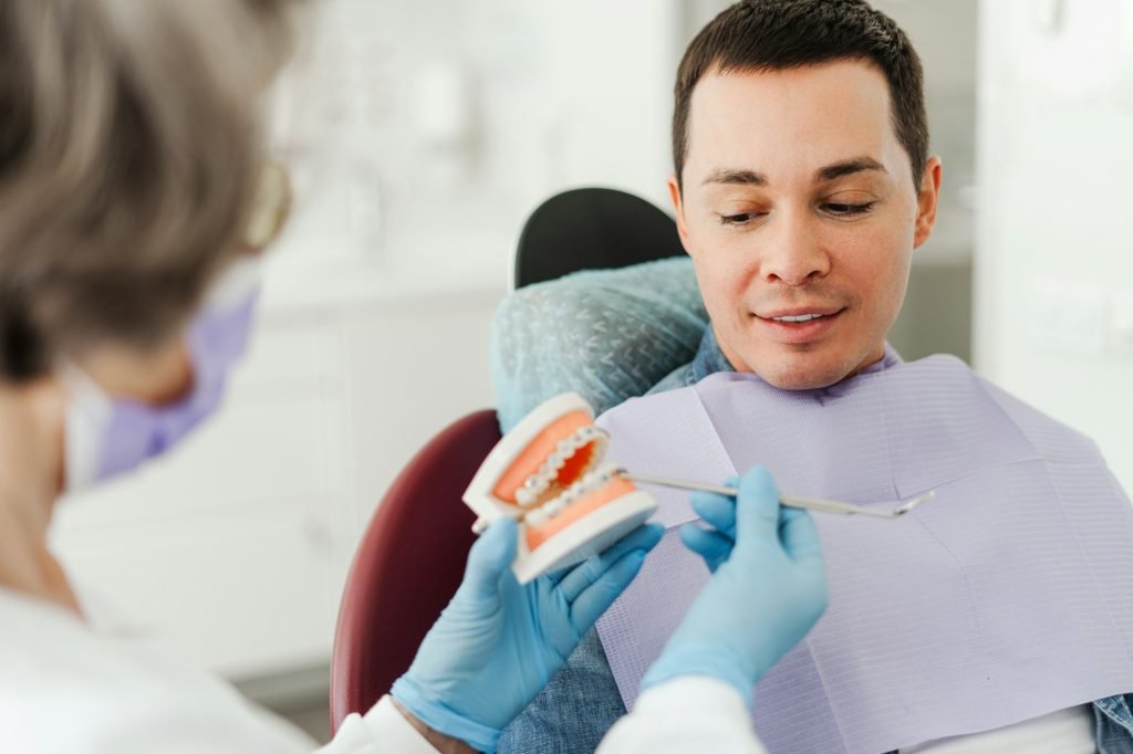 Professional, mature, female dentist, orthodontist holding jaw with braces, talking to patient